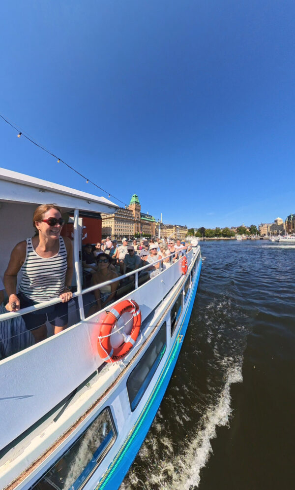 Kvinna på skärgårdsbåt med Stockholm i bakgrunden